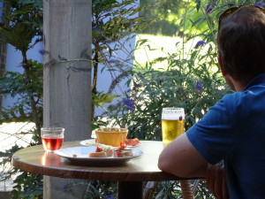 Een man aan tafel met een biertje en tapas op een kleine camping in Frankrijk